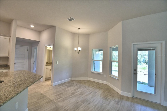 unfurnished dining area featuring light wood-type flooring, baseboards, visible vents, recessed lighting, and an inviting chandelier