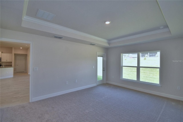 unfurnished room with baseboards, a tray ceiling, visible vents, and crown molding