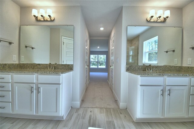 full bath with a tile shower, a sink, two vanities, baseboards, and wood tiled floor