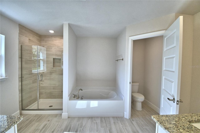 bathroom with toilet, vanity, a garden tub, a shower stall, and baseboards