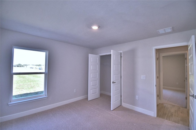 unfurnished bedroom featuring light carpet, baseboards, visible vents, and a closet