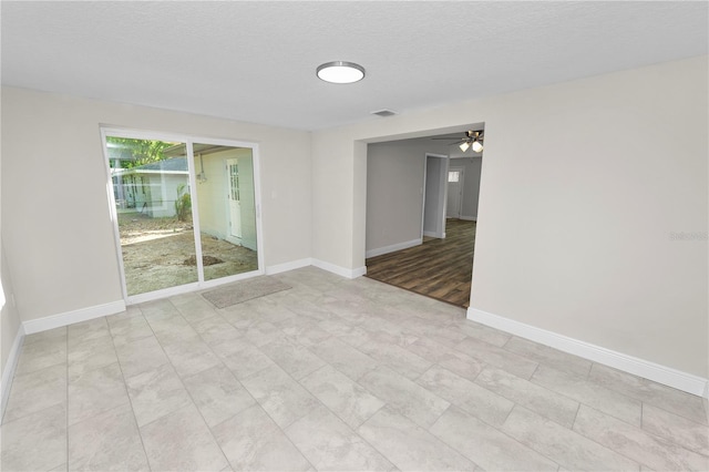 unfurnished room with visible vents, baseboards, ceiling fan, and a textured ceiling