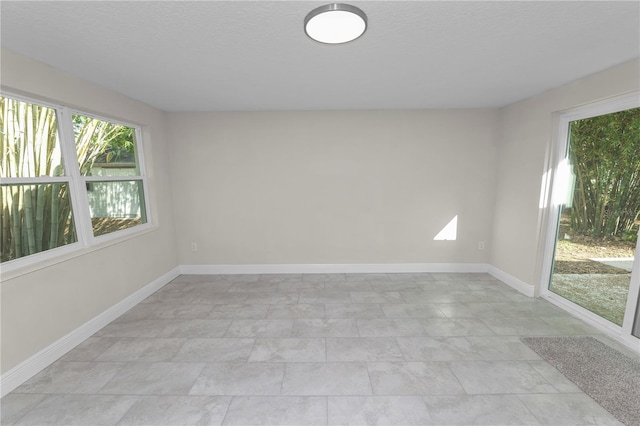 unfurnished room featuring a textured ceiling and baseboards