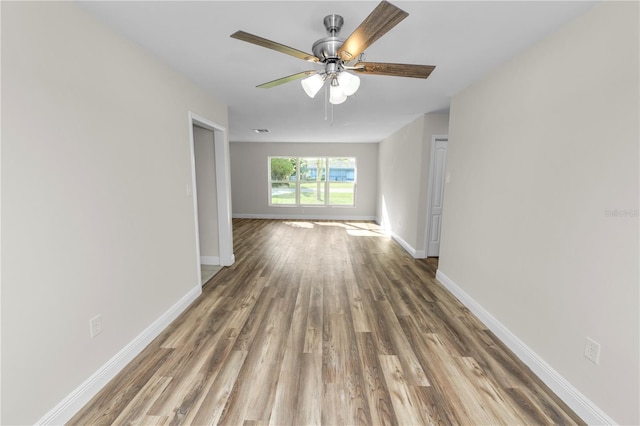 empty room with baseboards, a ceiling fan, and wood finished floors