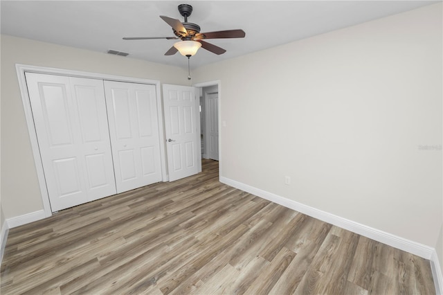 unfurnished bedroom featuring light wood-style floors, a closet, baseboards, and visible vents