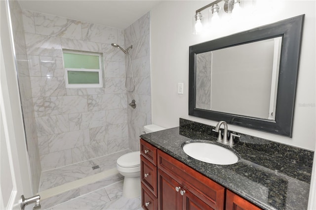 bathroom featuring toilet, tiled shower, marble finish floor, and vanity