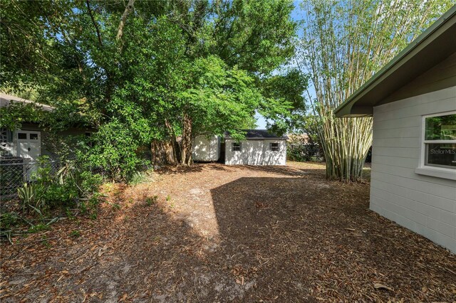view of yard with a storage shed, an outbuilding, and fence