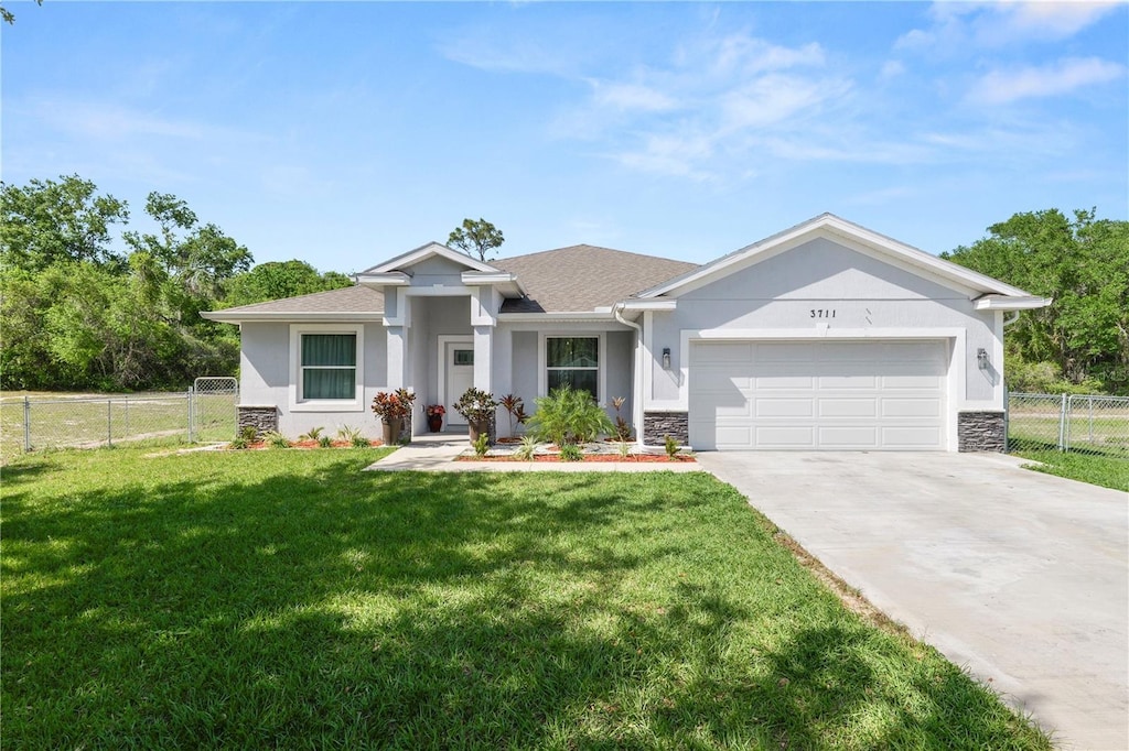 view of front of house with stucco siding, driveway, a front yard, a garage, and fence