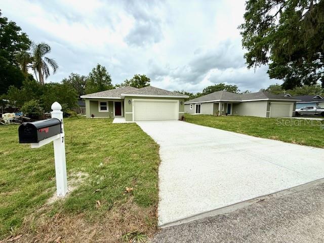 ranch-style house with an attached garage, stucco siding, driveway, and a front lawn