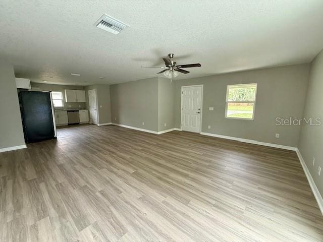 unfurnished living room with visible vents, baseboards, ceiling fan, a textured ceiling, and wood finished floors