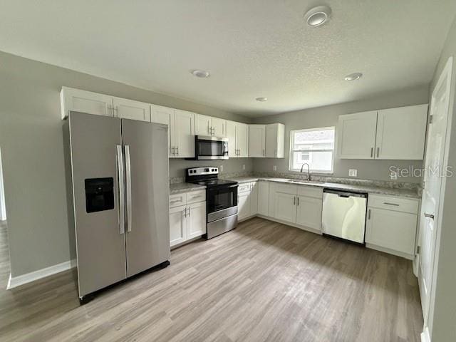kitchen featuring appliances with stainless steel finishes, a sink, light countertops, and white cabinetry