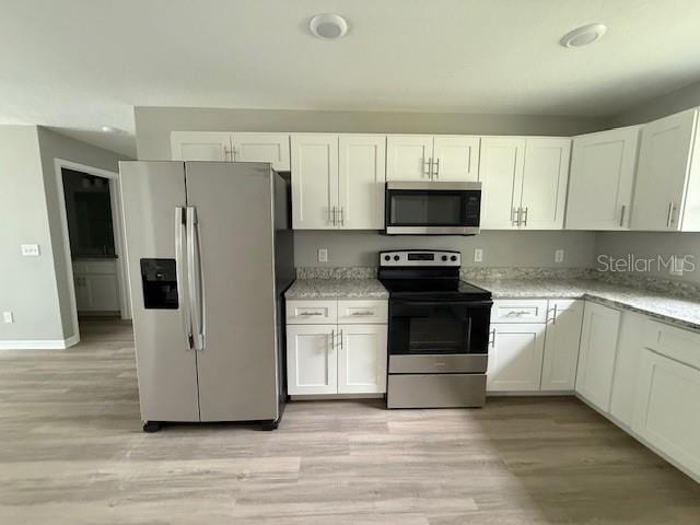 kitchen featuring white cabinets, appliances with stainless steel finishes, and light stone counters
