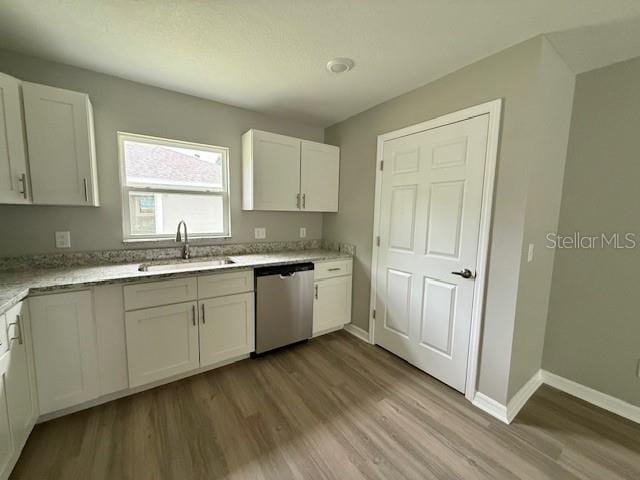 kitchen with white cabinets, baseboards, dishwasher, a sink, and wood finished floors