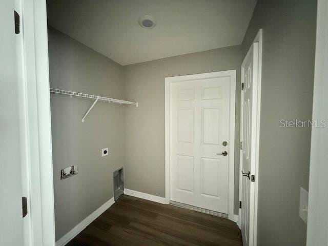 laundry area featuring baseboards, electric dryer hookup, laundry area, and dark wood finished floors