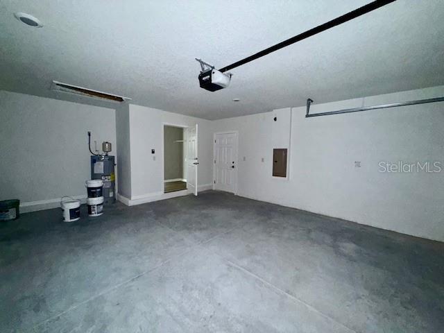 garage with water heater, a garage door opener, and electric panel