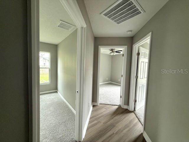 hallway featuring baseboards and visible vents