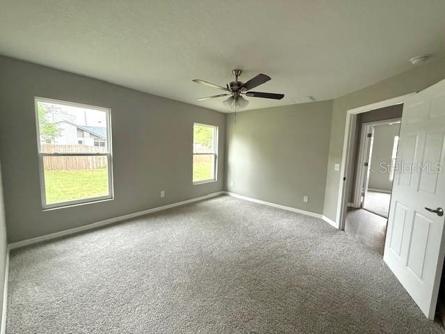 unfurnished room featuring carpet flooring, baseboards, and a ceiling fan