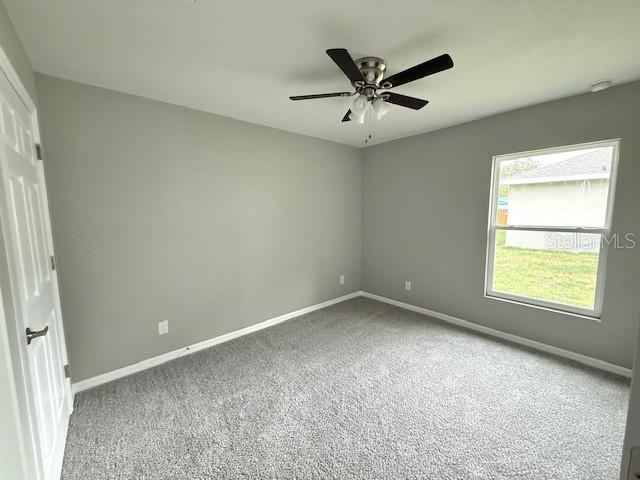carpeted spare room with baseboards and a ceiling fan