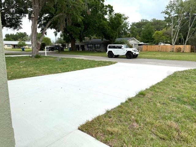 exterior space featuring a yard, driveway, and fence