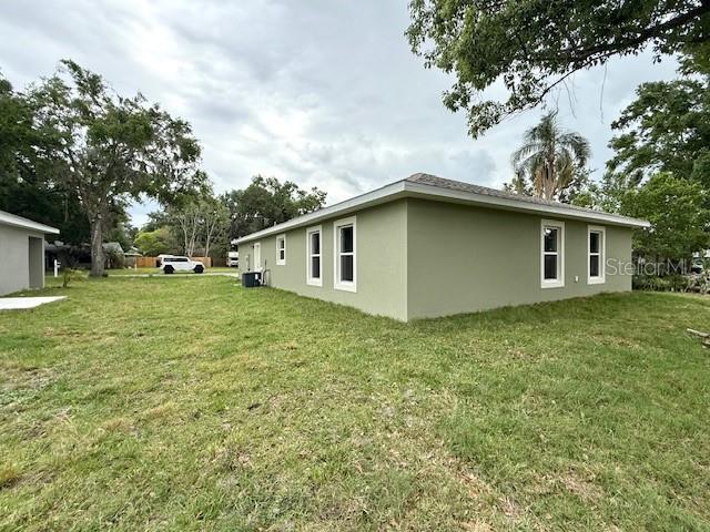 view of property exterior with a yard, stucco siding, and central AC