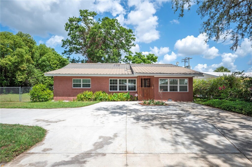 1440 E Conant St, Bartow, FL 33830 - view of front facade with concrete driveway, metal roof, and fence