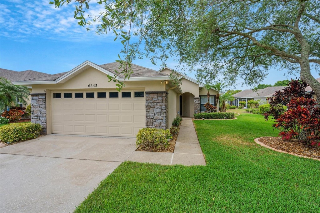 6545 Lake Clark Dr, Lakeland, FL 33813 - single story home featuring a garage, a front lawn, stucco siding, and stone siding