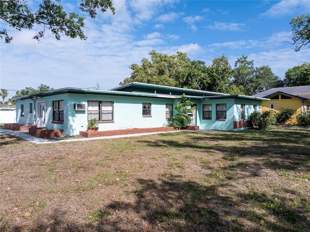 ranch-style home with a wall mounted AC and a front lawn