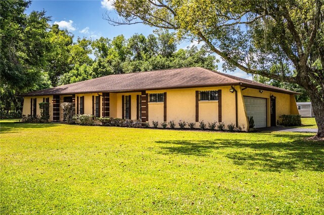 4101 N Forbes Rd, Plant City, FL 33565 - ranch-style home with stucco siding, an attached garage, a front lawn, and driveway