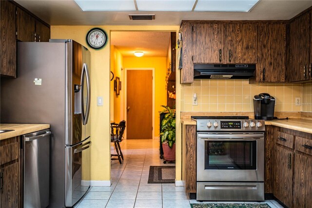 4101 N Forbes Rd, Plant City, FL 33565 - kitchen with under cabinet range hood, appliances with stainless steel finishes, dark brown cabinetry, and tasteful backsplash