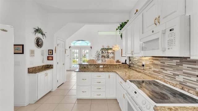 1062 Rally Dr, Polk City, FL 33868 - kitchen with light tile patterned floors, white cabinets, white appliances, a peninsula, and backsplash