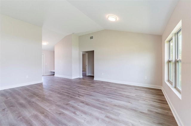 empty room with visible vents, baseboards, wood finished floors, and lofted ceiling