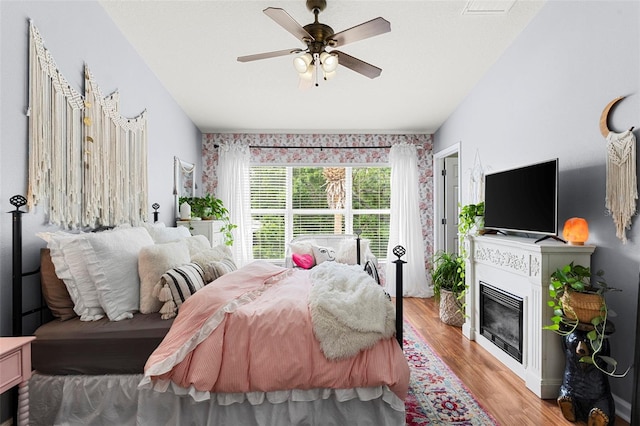 2125 Wild Grape Pl, Riverview, FL 33578 - bedroom with light wood-style floors, a glass covered fireplace, and a ceiling fan