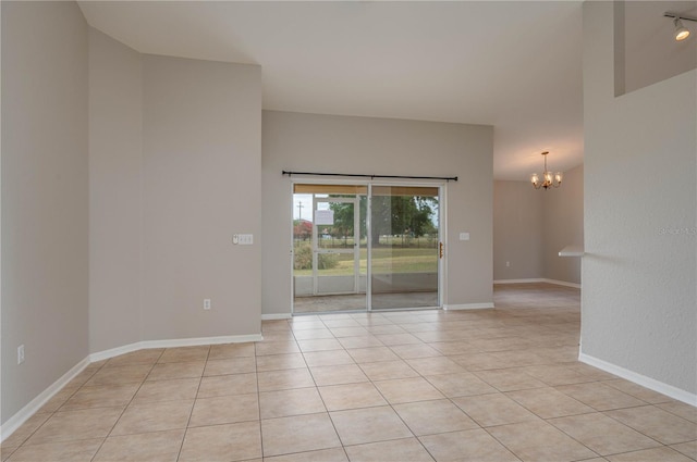 spare room with light tile patterned floors, a notable chandelier, and baseboards