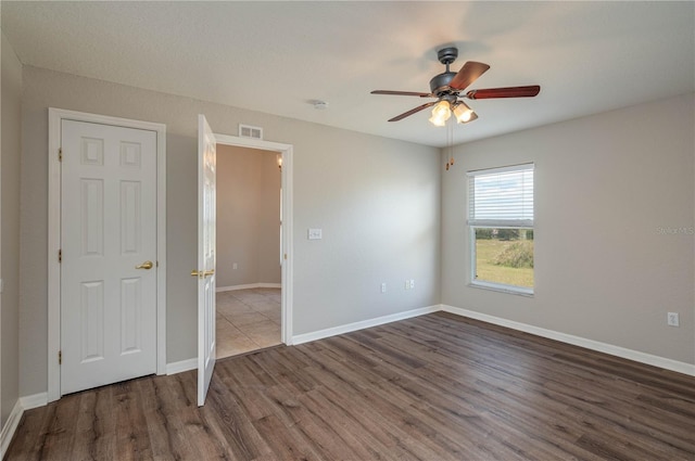 unfurnished bedroom featuring wood finished floors, baseboards, a ceiling fan, and visible vents
