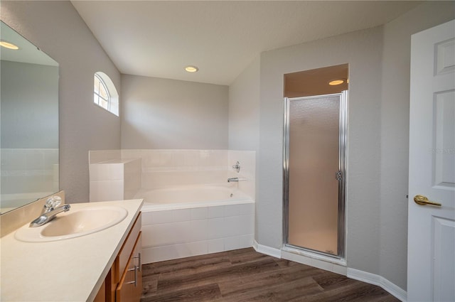 bathroom featuring vanity, baseboards, a shower stall, a bath, and wood finished floors