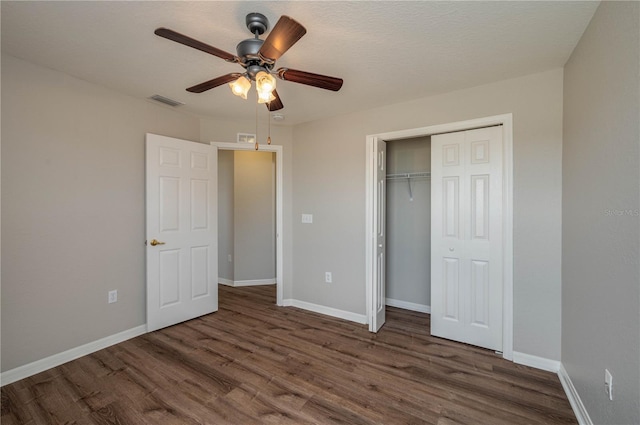 unfurnished bedroom featuring visible vents, a closet, baseboards, and wood finished floors