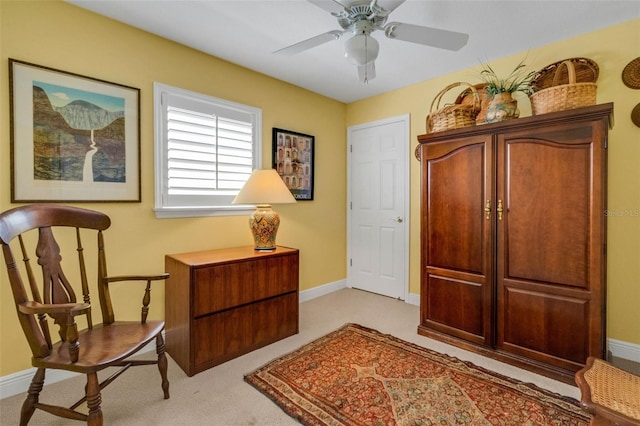 sitting room with light carpet, a ceiling fan, and baseboards
