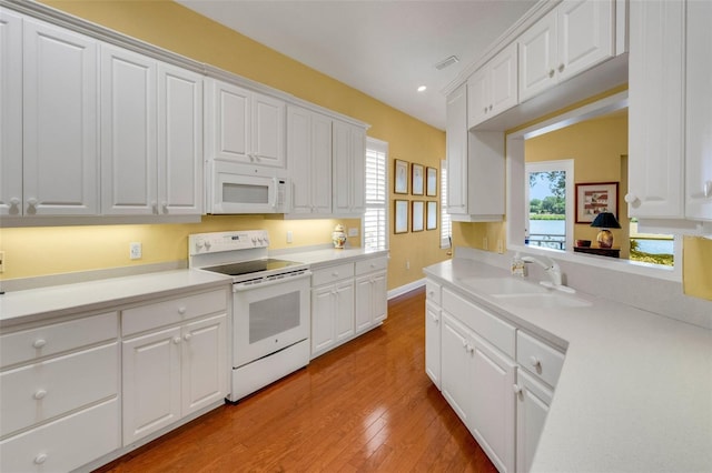 kitchen featuring light wood-style floors, white cabinetry, a sink, and white appliances