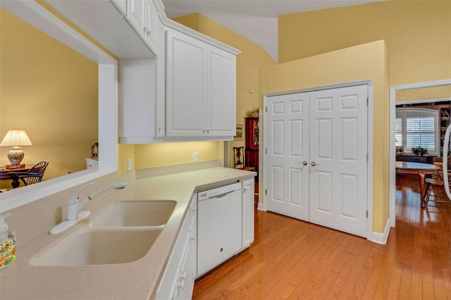 kitchen with light countertops, a sink, light wood-style floors, white cabinetry, and dishwasher