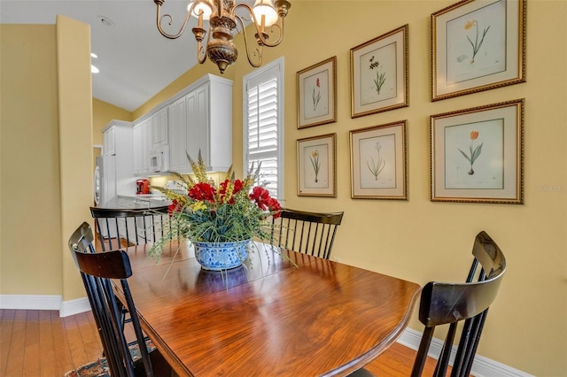 dining room with baseboards, wood finished floors, and a chandelier