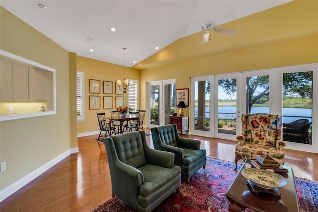 living area featuring recessed lighting, lofted ceiling, wood finished floors, a water view, and baseboards