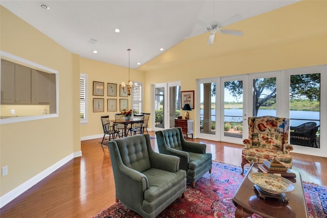 living room featuring vaulted ceiling, wood finished floors, a water view, baseboards, and recessed lighting