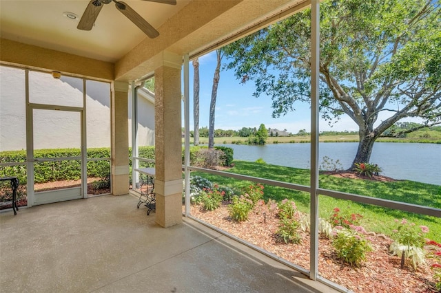 unfurnished sunroom featuring a water view and a ceiling fan