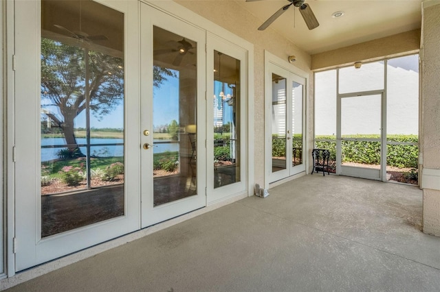 unfurnished sunroom with ceiling fan, french doors, and a water view