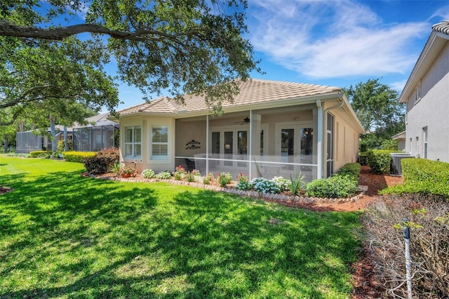 back of property featuring a tiled roof, a ceiling fan, a yard, and stucco siding