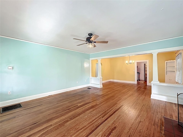 interior space with decorative columns, visible vents, ceiling fan with notable chandelier, and hardwood / wood-style floors