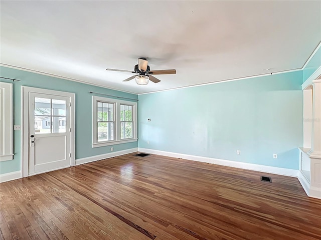 unfurnished room with ornamental molding, a ceiling fan, visible vents, wood finished floors, and baseboards