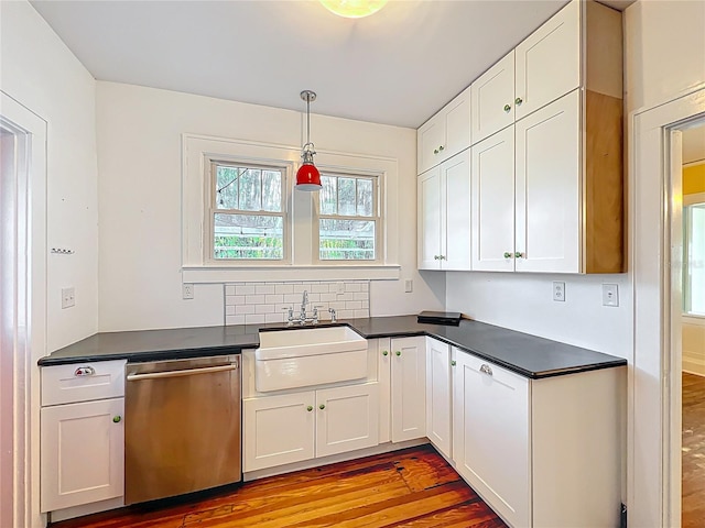 kitchen featuring stainless steel dishwasher, light wood-style flooring, a sink, and dark countertops