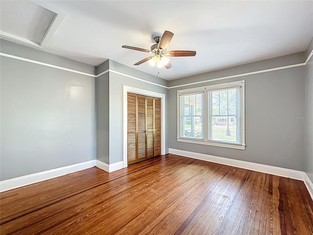 unfurnished bedroom with hardwood / wood-style floors, a closet, baseboards, and a ceiling fan