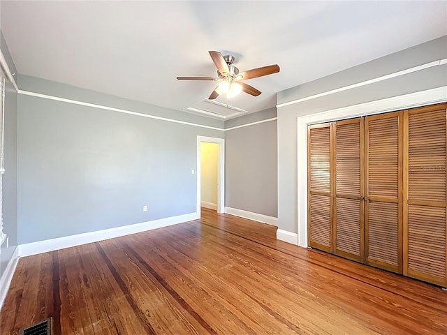 unfurnished bedroom featuring visible vents, a closet, baseboards, ceiling fan, and wood finished floors